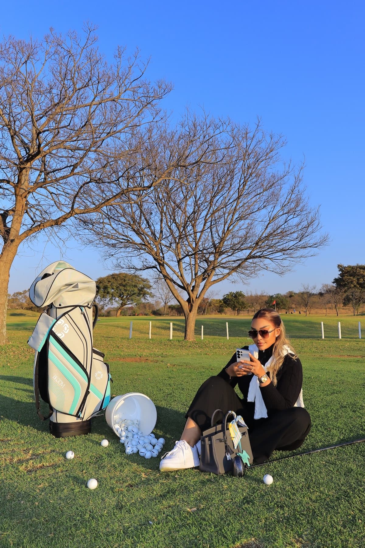 Zari checking her phone on the green