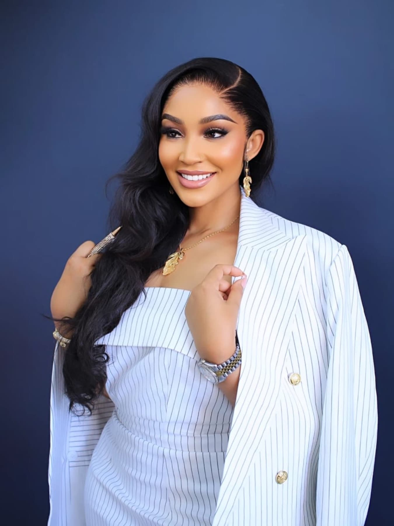 Zari smiling in a white pinstripe suit